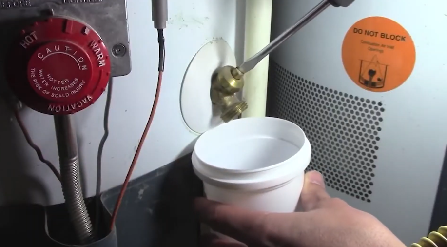 Draining sediment from a tank water heater into a bucket at the drain valve