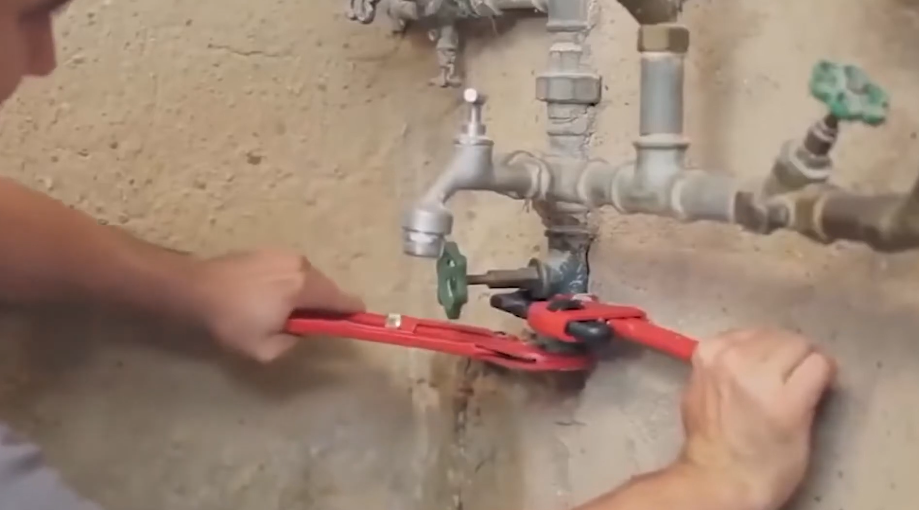 Closing the main water shutoff valve on the exterior wall of a house