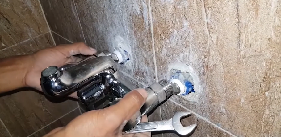 Setting a chrome shower valve trim into a tiled wall with a wrench