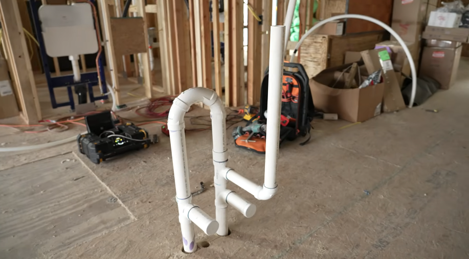 Assembled PVC drain and vent stack standing ready in a framed room