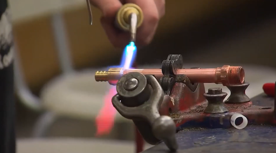 Soldering a copper fitting with a torch at a workbench