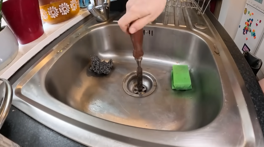 Clearing and cleaning the drain opening of a stainless steel kitchen sink