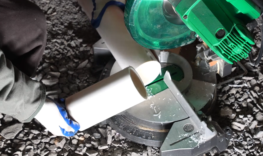 White PVC sewer pipe and fitting bedded in a gravel trench