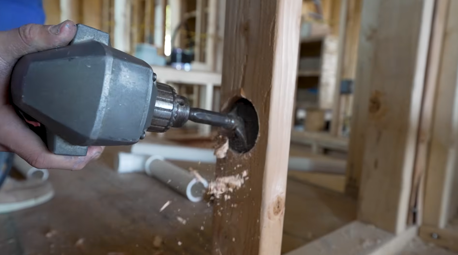 Breaking through a concrete floor with a hammer drill to reach a pipe below