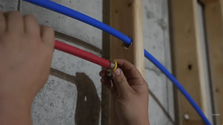 Plumber checking red and blue PEX water lines inside a wall during leak detection in Tustin Meadows